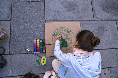 Das Logo von Fridays For Future wird auf ein Schild am Boden gemalt.